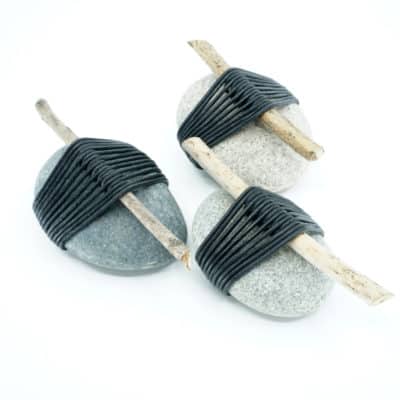 Side view of three wrapped rocks with leather cord and sticks