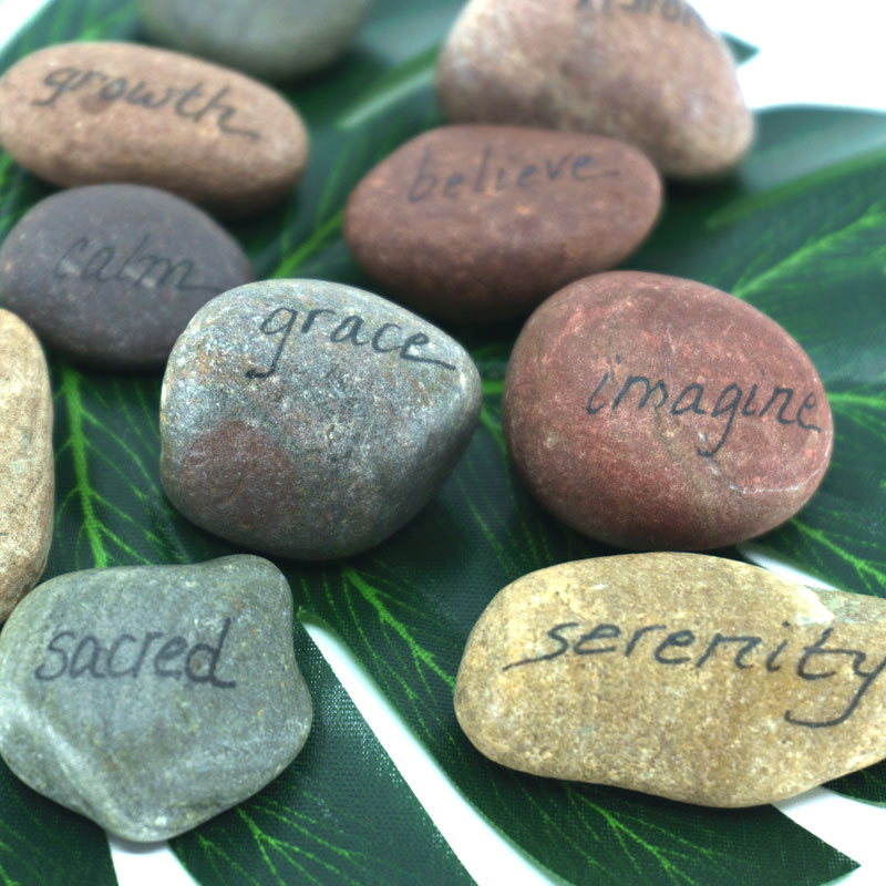 Closeup of A mix of stones with words written on them like create, sacred, serenity, and grace